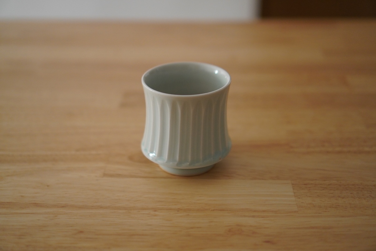 木のテーブルの上に置かれたシンプルな湯のみカップ